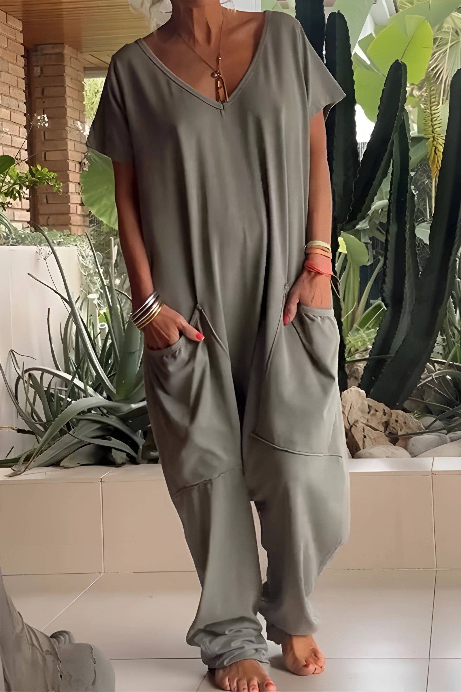 Woman wearing an army green oversized jumpsuit with a V-neck and pockets, styled in a boho chic fashion.